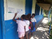 School children reviewing the Vanuatu Climate Update (VCU) placed on community and school notice boards. 